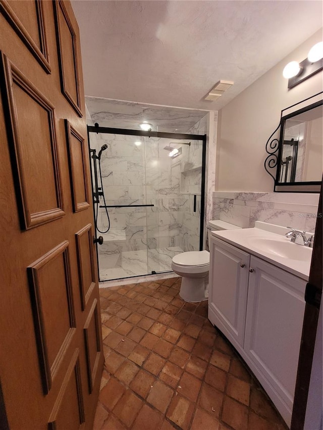 bathroom with vanity, tile walls, an enclosed shower, and toilet