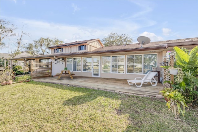 rear view of house featuring a wooden deck and a yard