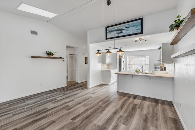 unfurnished living room featuring sink, wood-type flooring, and lofted ceiling with skylight