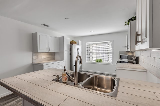 kitchen featuring sink, backsplash, stainless steel appliances, and hardwood / wood-style flooring