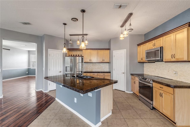 2707 Atlantis Dr, New Smyrna Beach, FL 32168 - kitchen featuring light tile patterned flooring, decorative light fixtures, a center island with sink, stainless steel appliances, and backsplash