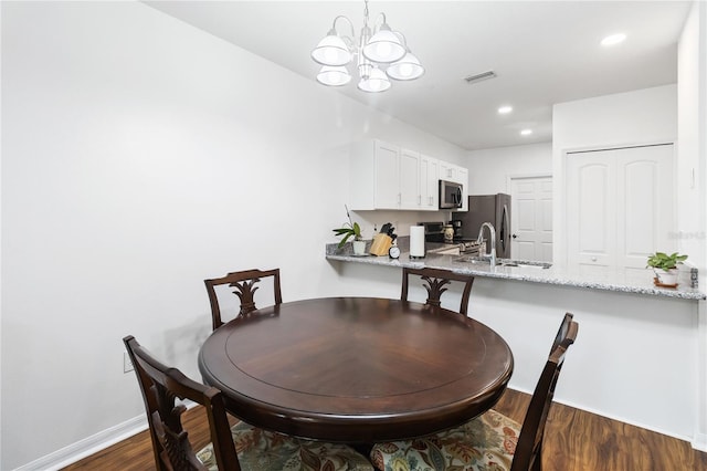 dining room featuring sink, an inviting chandelier, and dark hardwood / wood-style flooring