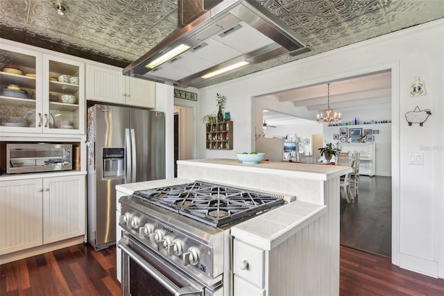 kitchen with decorative light fixtures, dark hardwood / wood-style floors, wall chimney range hood, an inviting chandelier, and stainless steel appliances