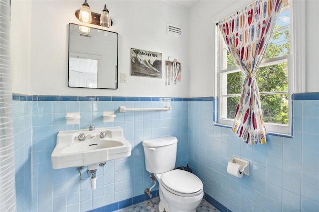 bathroom with toilet, tile walls, and sink