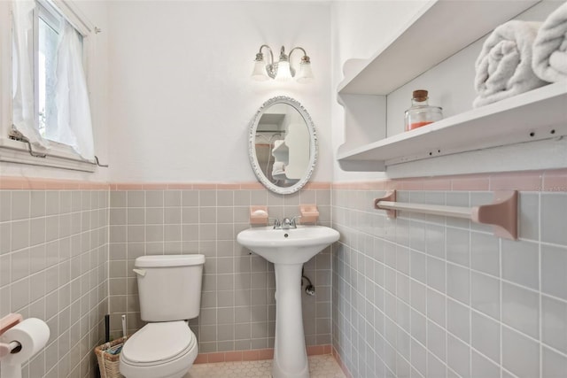 bathroom with toilet, tile patterned flooring, and tile walls