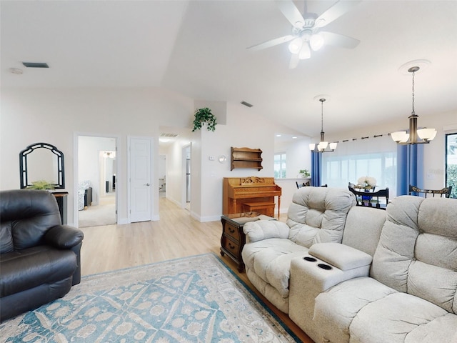 living room with ceiling fan with notable chandelier, vaulted ceiling, and light hardwood / wood-style floors