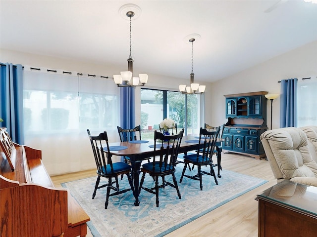 dining space with lofted ceiling, light hardwood / wood-style flooring, and an inviting chandelier