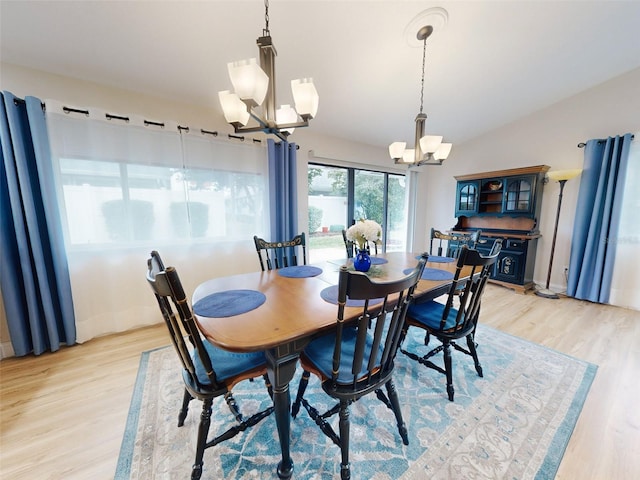 dining area featuring a notable chandelier, vaulted ceiling, and light hardwood / wood-style floors