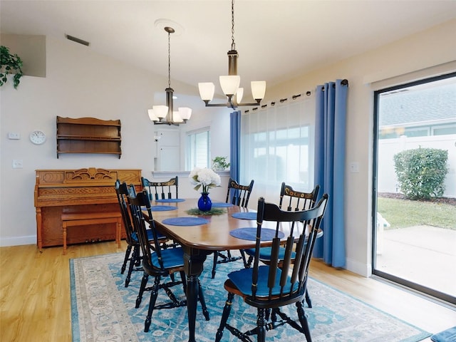 dining room with vaulted ceiling, light wood-type flooring, and a chandelier