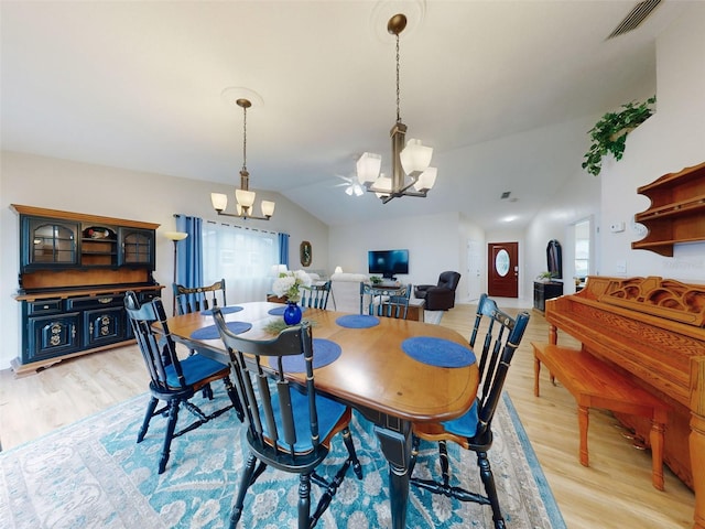 dining space featuring vaulted ceiling, a chandelier, and light wood-type flooring