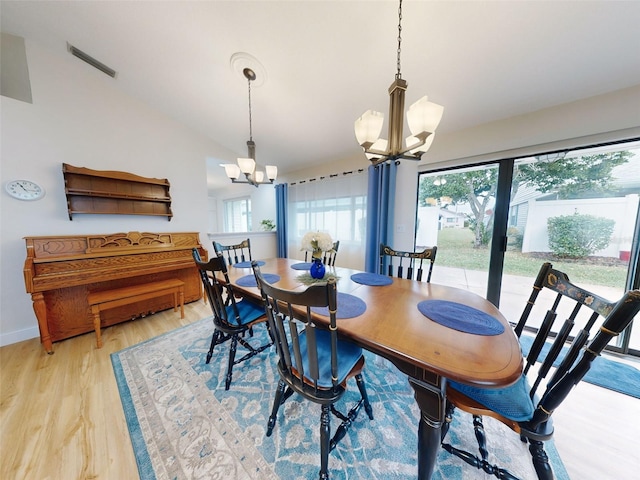 dining room featuring vaulted ceiling, light wood-type flooring, and a chandelier