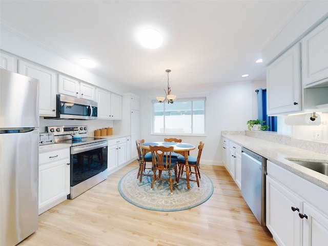 kitchen featuring hanging light fixtures, light stone countertops, appliances with stainless steel finishes, and white cabinets