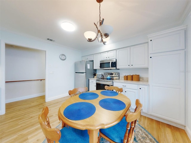 kitchen with pendant lighting, crown molding, light hardwood / wood-style flooring, white cabinetry, and stainless steel appliances