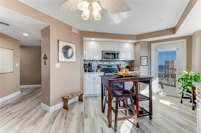 kitchen with white cabinetry, decorative backsplash, stainless steel appliances, and light wood-type flooring