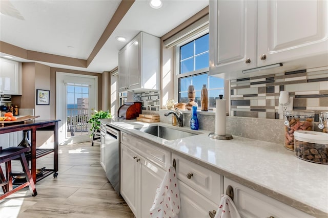 kitchen featuring white cabinetry, backsplash, sink, and a wealth of natural light