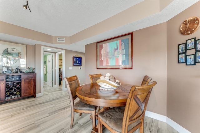 dining room featuring a textured ceiling and light wood-type flooring