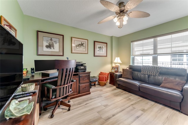 home office with a textured ceiling, ceiling fan, and light hardwood / wood-style floors