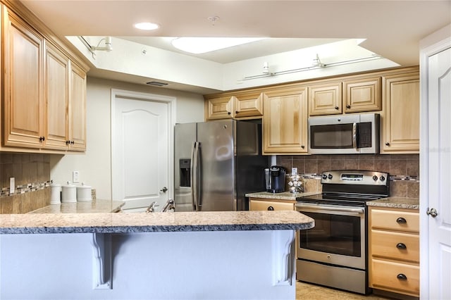 kitchen with stainless steel appliances, kitchen peninsula, decorative backsplash, and light brown cabinets