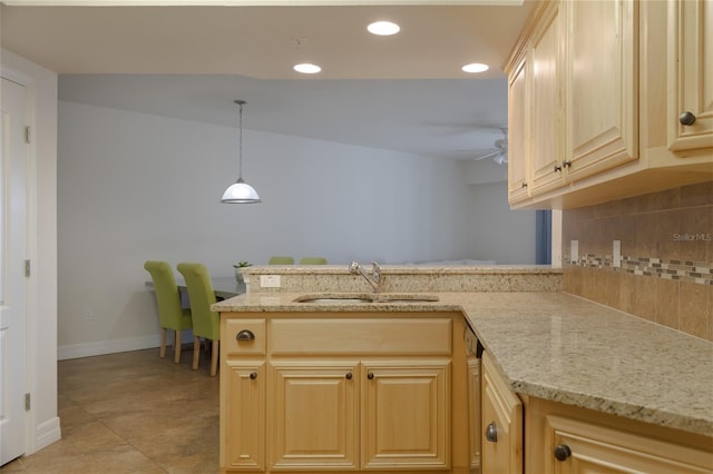 kitchen featuring light brown cabinetry, decorative light fixtures, tasteful backsplash, sink, and kitchen peninsula