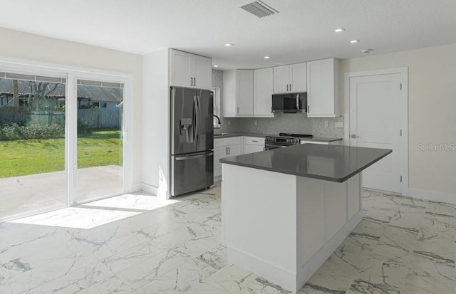 kitchen with white cabinetry, sink, decorative backsplash, a center island, and stainless steel appliances