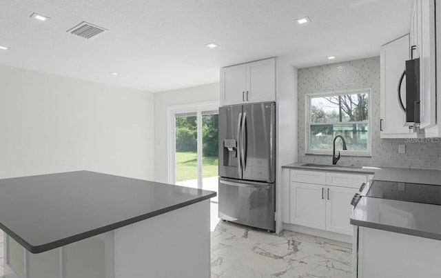 kitchen featuring a kitchen island, white cabinetry, sink, decorative backsplash, and stainless steel refrigerator with ice dispenser