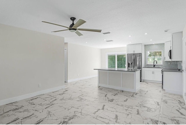 kitchen with sink, white cabinets, decorative backsplash, a center island, and stainless steel fridge with ice dispenser