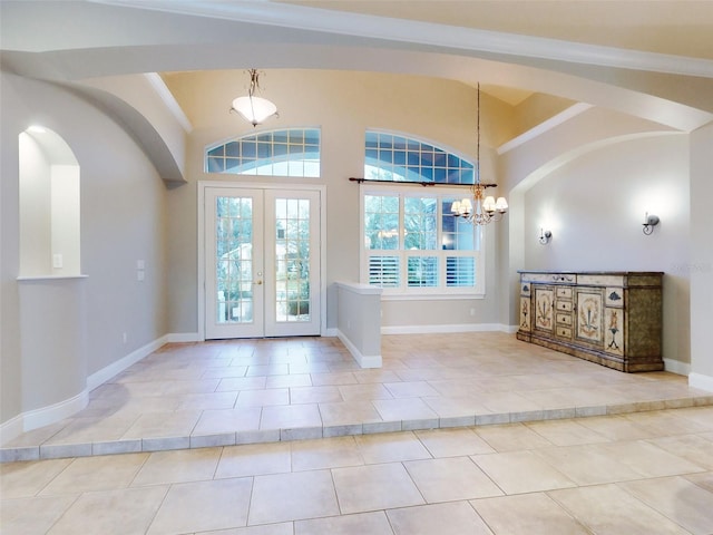 foyer with light tile patterned floors, crown molding, french doors, and a chandelier