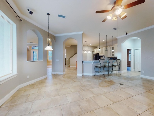 kitchen featuring appliances with stainless steel finishes, a breakfast bar, decorative light fixtures, white cabinets, and ornamental molding