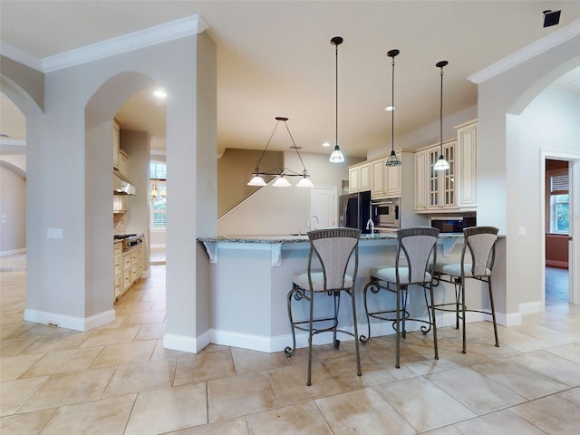 kitchen with stainless steel microwave, a breakfast bar area, black refrigerator, and cream cabinetry