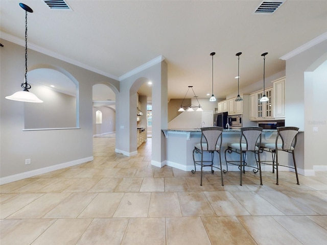 kitchen with stainless steel microwave, decorative light fixtures, ornamental molding, kitchen peninsula, and cream cabinetry