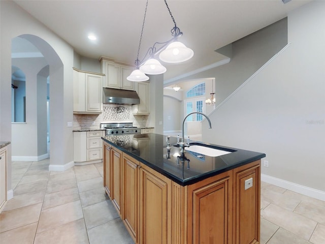 kitchen featuring crown molding, sink, decorative light fixtures, and an island with sink