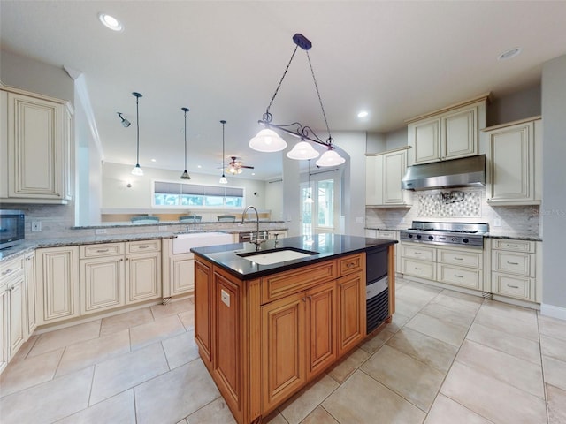 kitchen featuring pendant lighting, sink, appliances with stainless steel finishes, a kitchen island with sink, and cream cabinetry