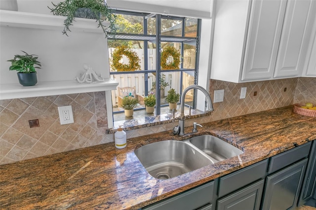 kitchen featuring gray cabinetry, backsplash, dark stone counters, white cabinets, and sink