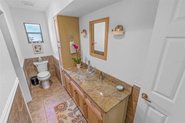 bathroom featuring tile patterned floors, tile walls, toilet, and vanity