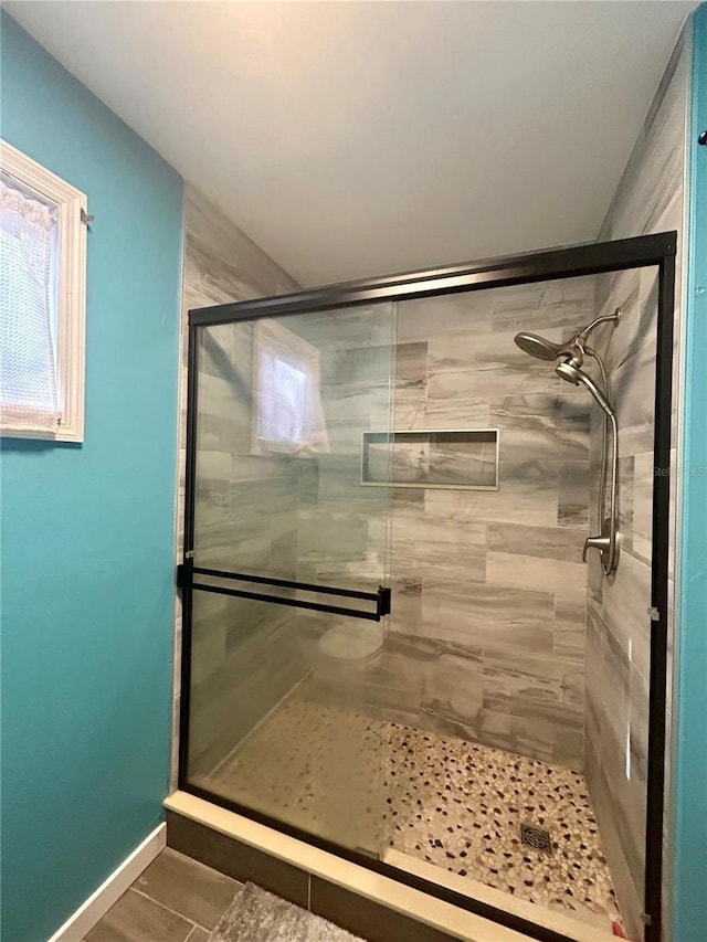 bathroom with a shower with door and tile patterned flooring