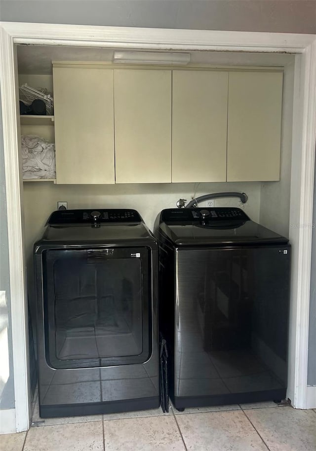 laundry room featuring light tile patterned flooring, cabinets, and washer and dryer