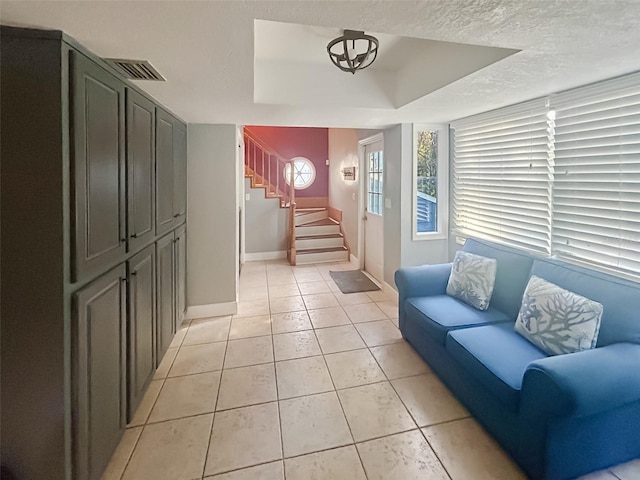 living room featuring a raised ceiling, a textured ceiling, and light tile patterned floors