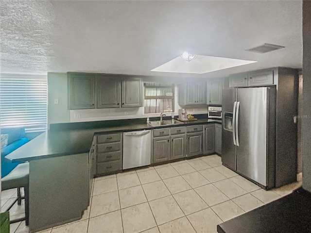 kitchen featuring sink, gray cabinets, appliances with stainless steel finishes, a textured ceiling, and light tile patterned flooring