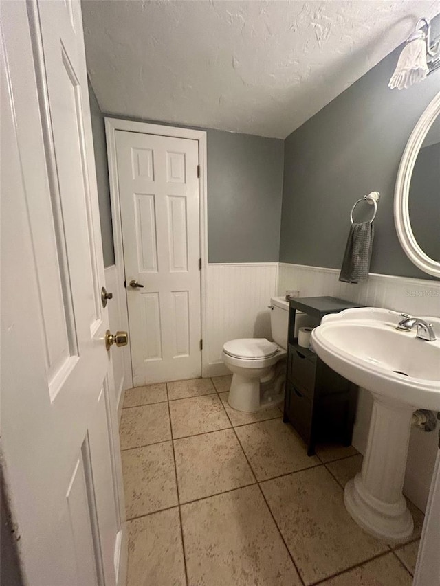 bathroom with tile patterned flooring, a textured ceiling, and toilet