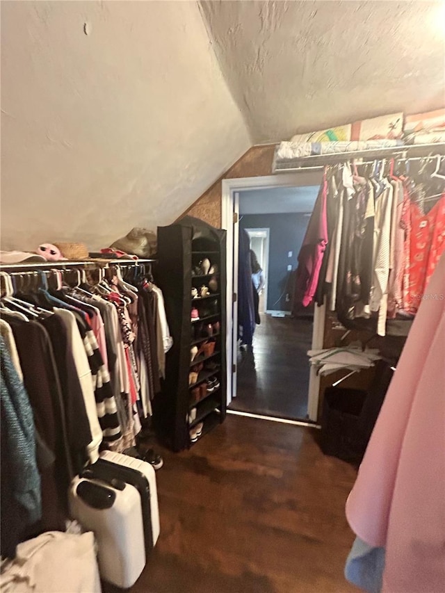 spacious closet with lofted ceiling and dark hardwood / wood-style floors