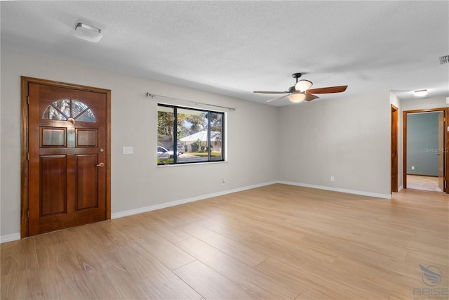 foyer entrance with ceiling fan, light hardwood / wood-style flooring, and a textured ceiling