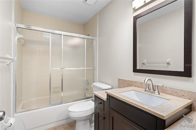 full bathroom featuring vanity, combined bath / shower with glass door, and toilet