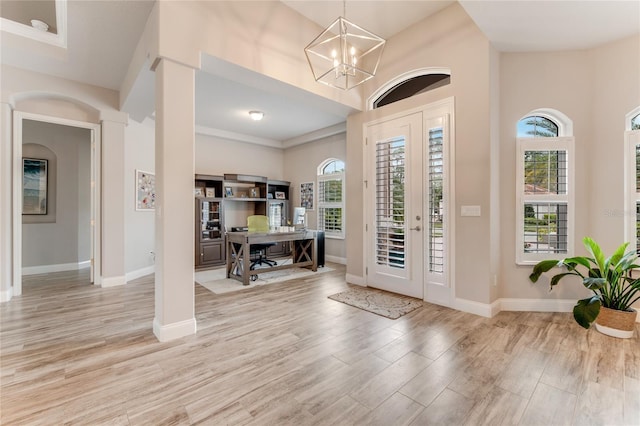 entryway featuring light hardwood / wood-style floors, a towering ceiling, a chandelier, and a healthy amount of sunlight