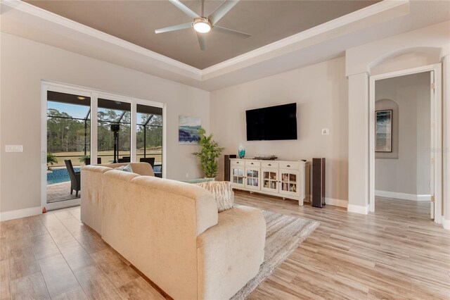 living room with ceiling fan, light hardwood / wood-style flooring, crown molding, and a tray ceiling