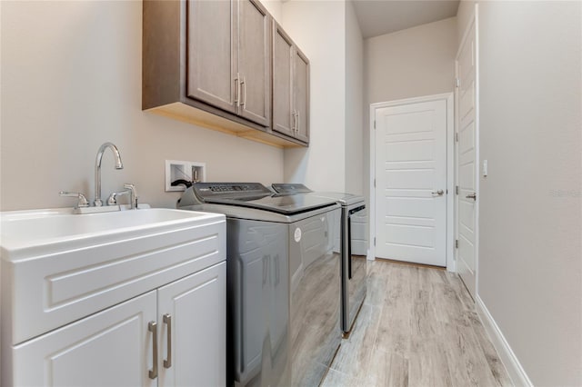 laundry room with cabinets, light hardwood / wood-style flooring, and washing machine and dryer