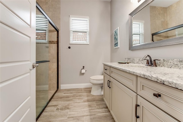 bathroom featuring a wealth of natural light, toilet, walk in shower, and vanity