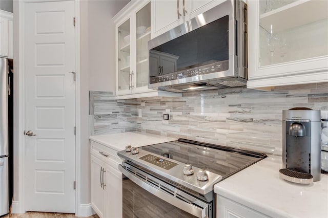 2824 S Asciano Ct, New Smyrna Beach, FL 32168 - kitchen with appliances with stainless steel finishes, tasteful backsplash, light countertops, white cabinets, and glass insert cabinets