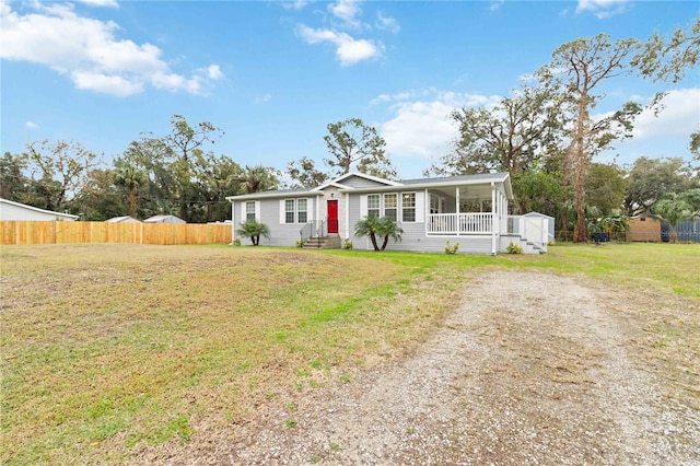 view of front facade featuring entry steps, covered porch, fence, and a front lawn