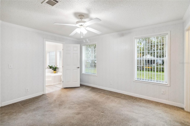 carpeted empty room with ceiling fan, ornamental molding, and a textured ceiling