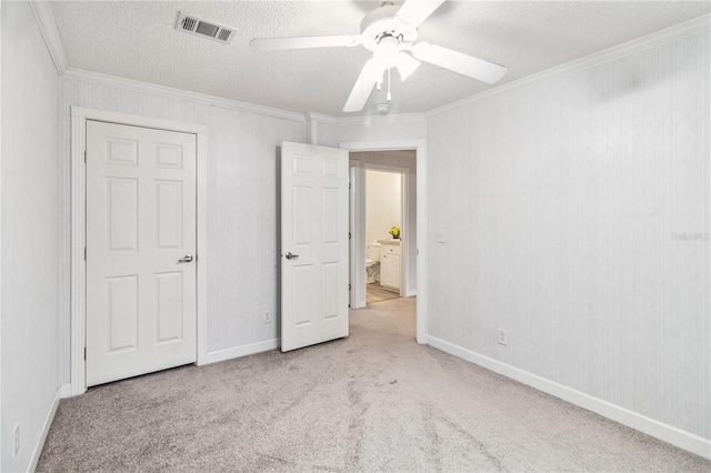 unfurnished bedroom with visible vents, a ceiling fan, carpet, crown molding, and a textured ceiling